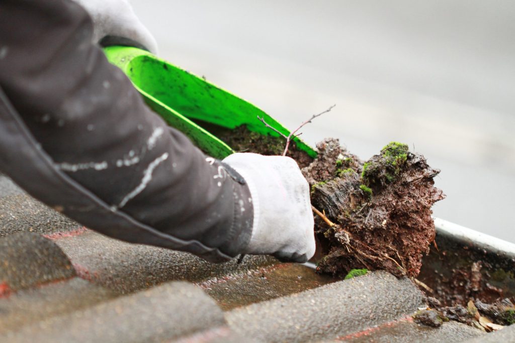 camberley-guttersvery-dirty-gutter-being-cleared-by-man-with-a-tool-and-hand-scaled